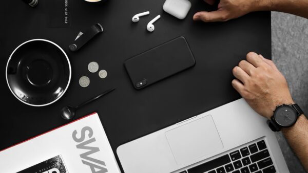 A contemporary workspace featuring tech devices, coffee, and a stylish magazine.